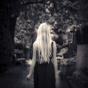 Blond girl walking alone at cemetery